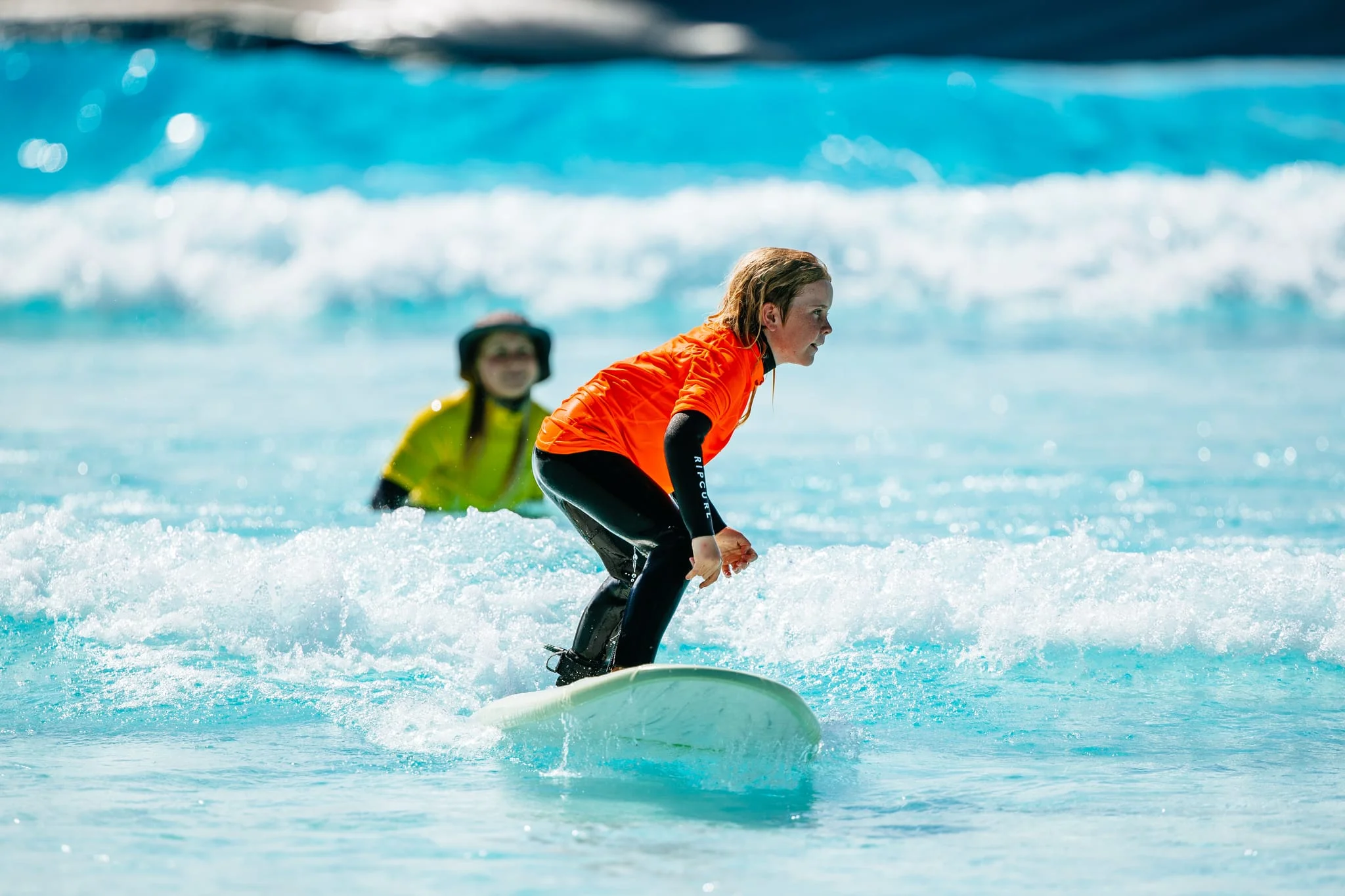 A photograph of a young person learning to surf at the URBNSURF Sydney wave pool.