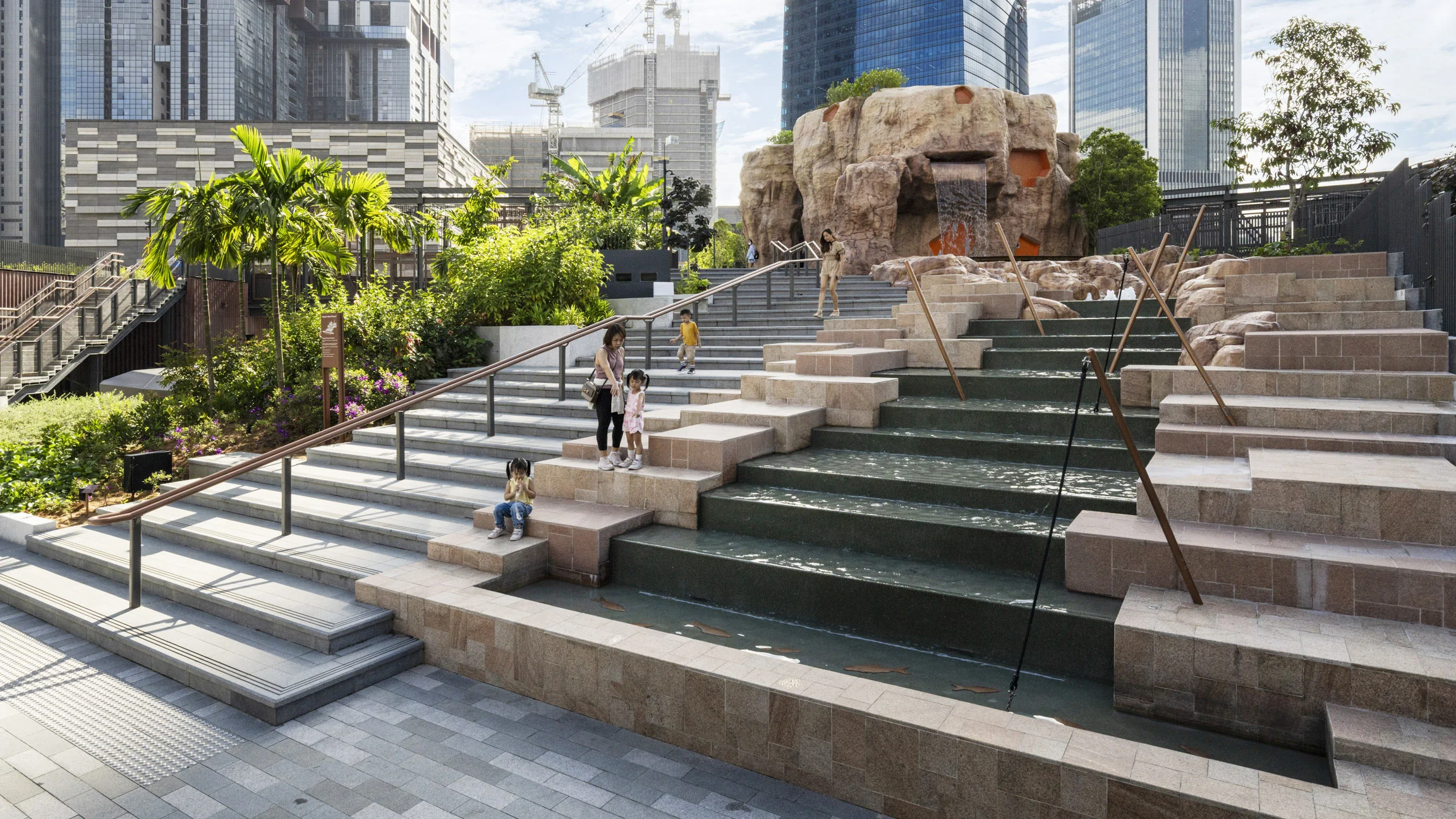 A photograph of a staircase in a rooftop park, beside a stepped water feature.