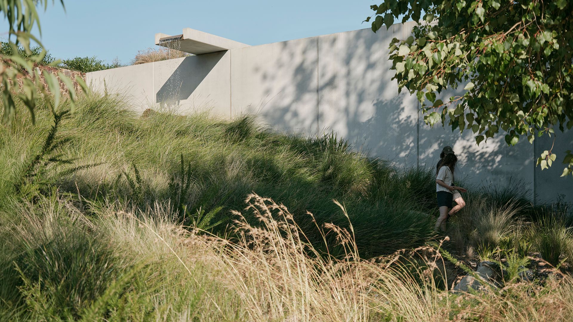 Exterior wall of museum complete with a water feature and a couple walking in the foreground 