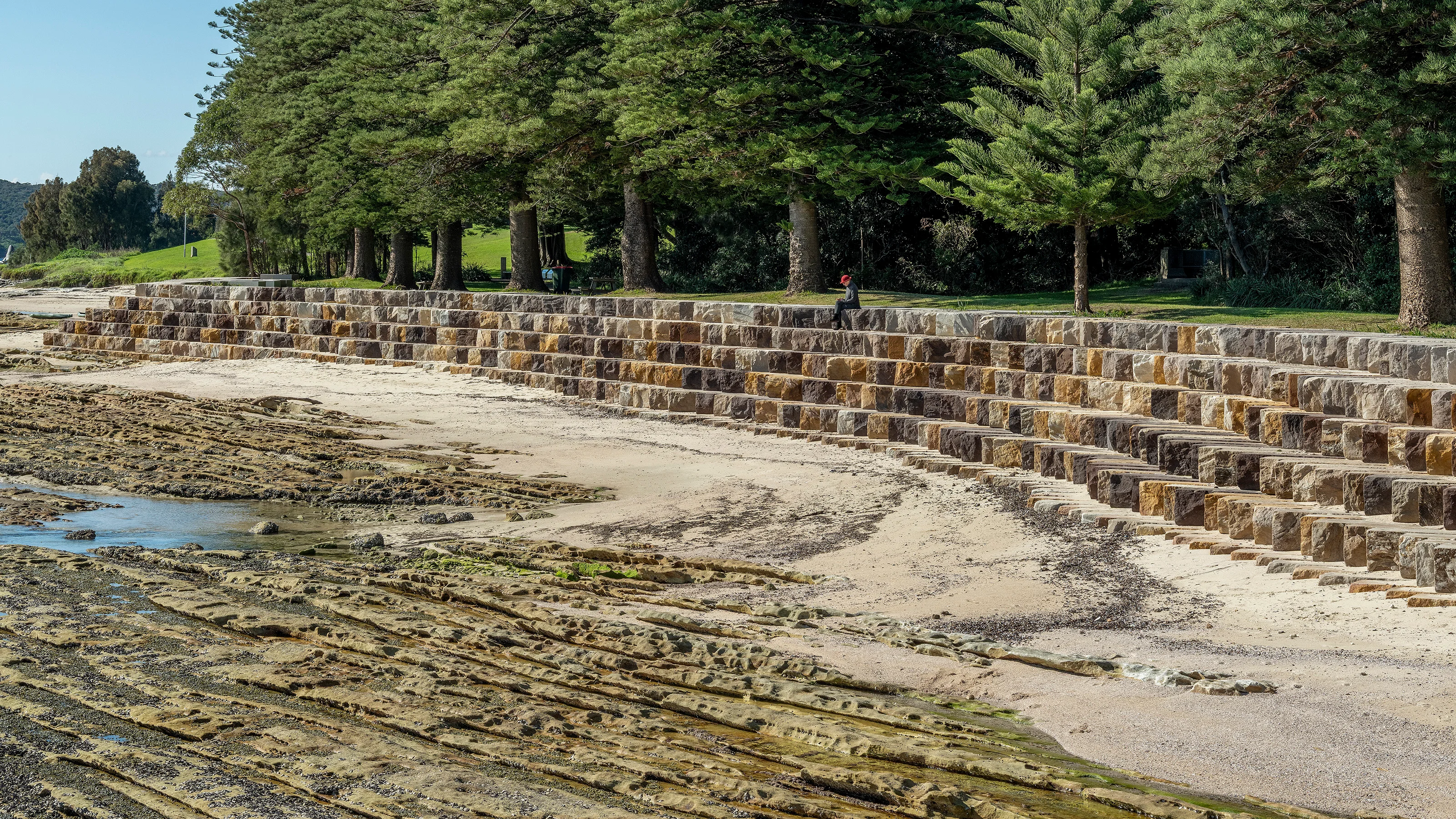 Sandstone wall separates rocky bay from parkland.