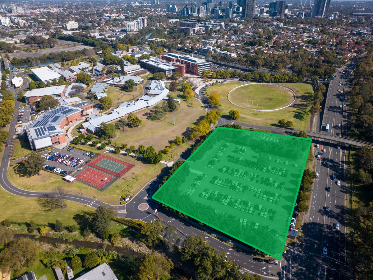 An aerial photograph of a university campus, a carpark in the foreground is highlighted with a green square to indicate the competition site.