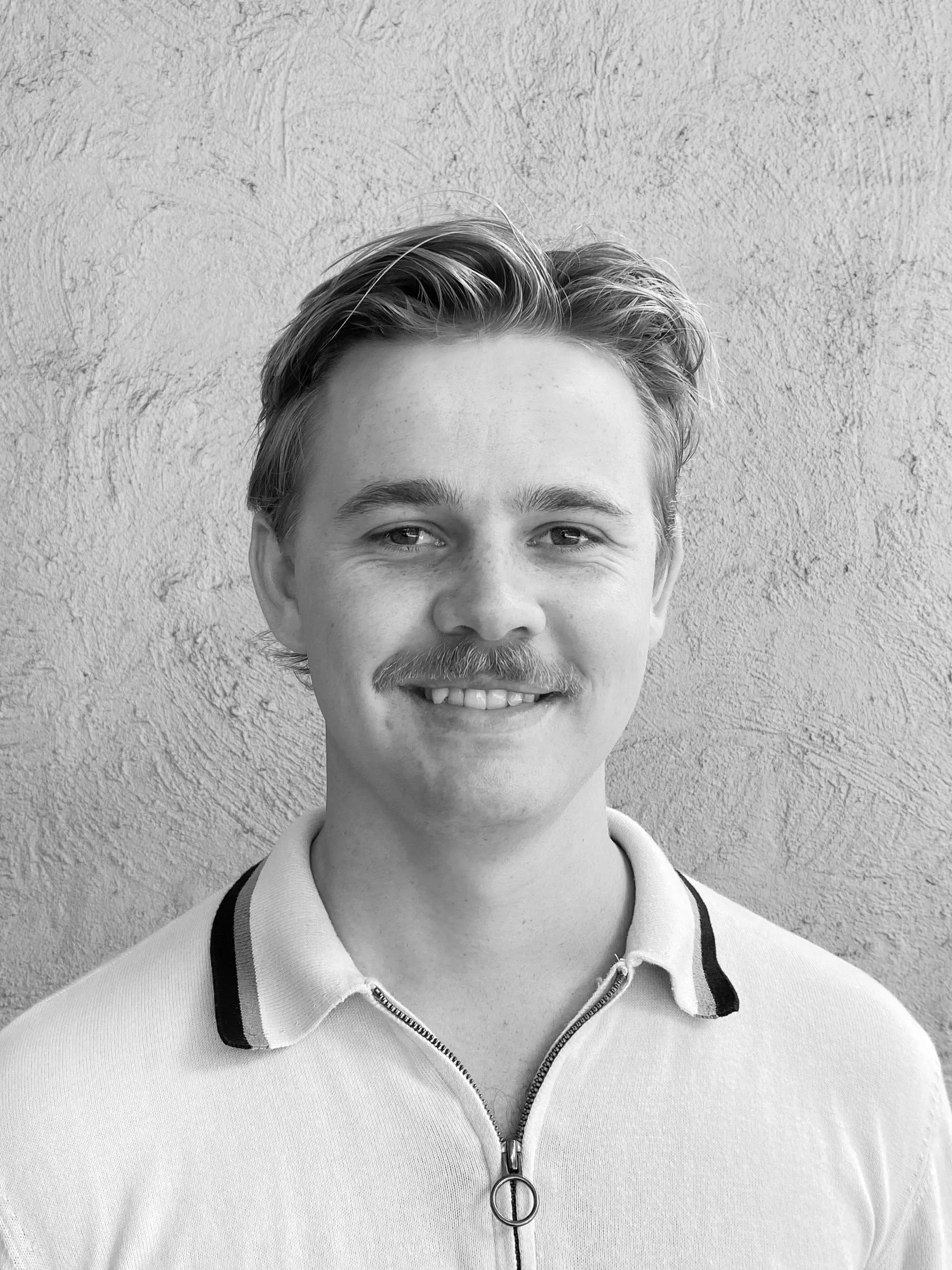 A black and white headshot of a person smiling.