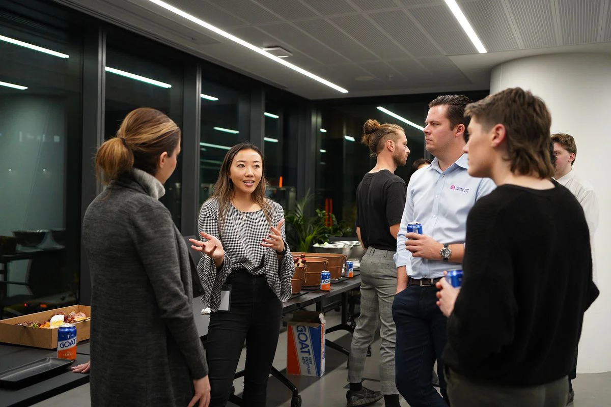 A small group of people, inside and office space, talking.
