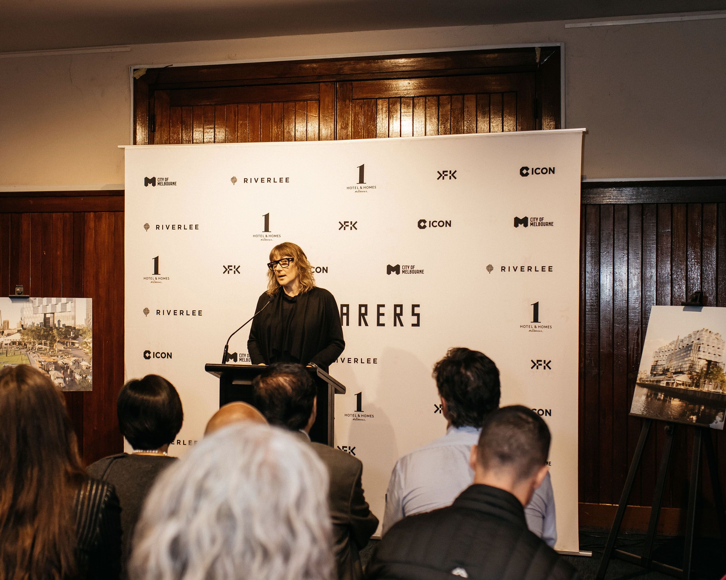 A photo of a person giving a speech in front of a media wall. 