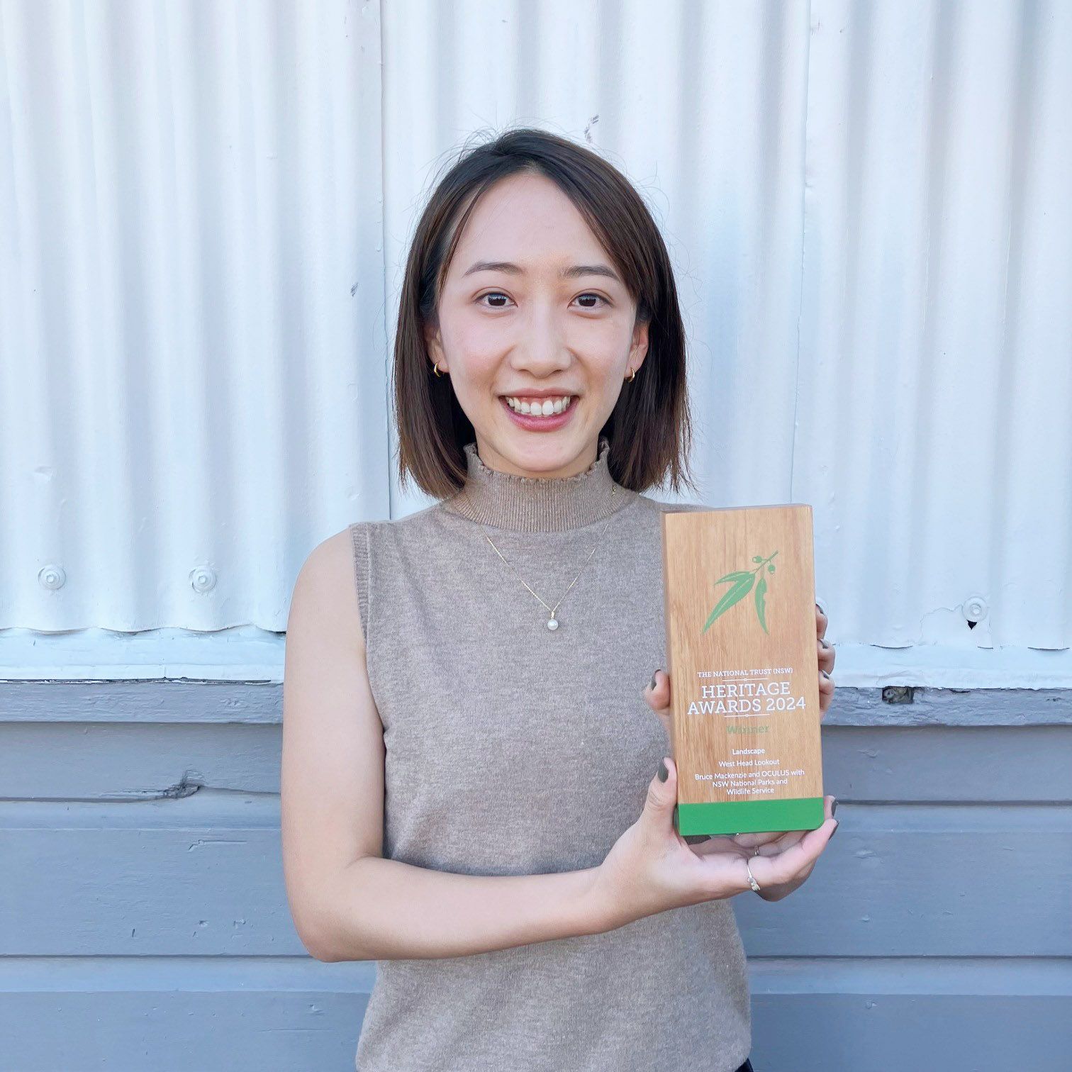 A photograph of a smiling person proudly holding a timber trophy. 