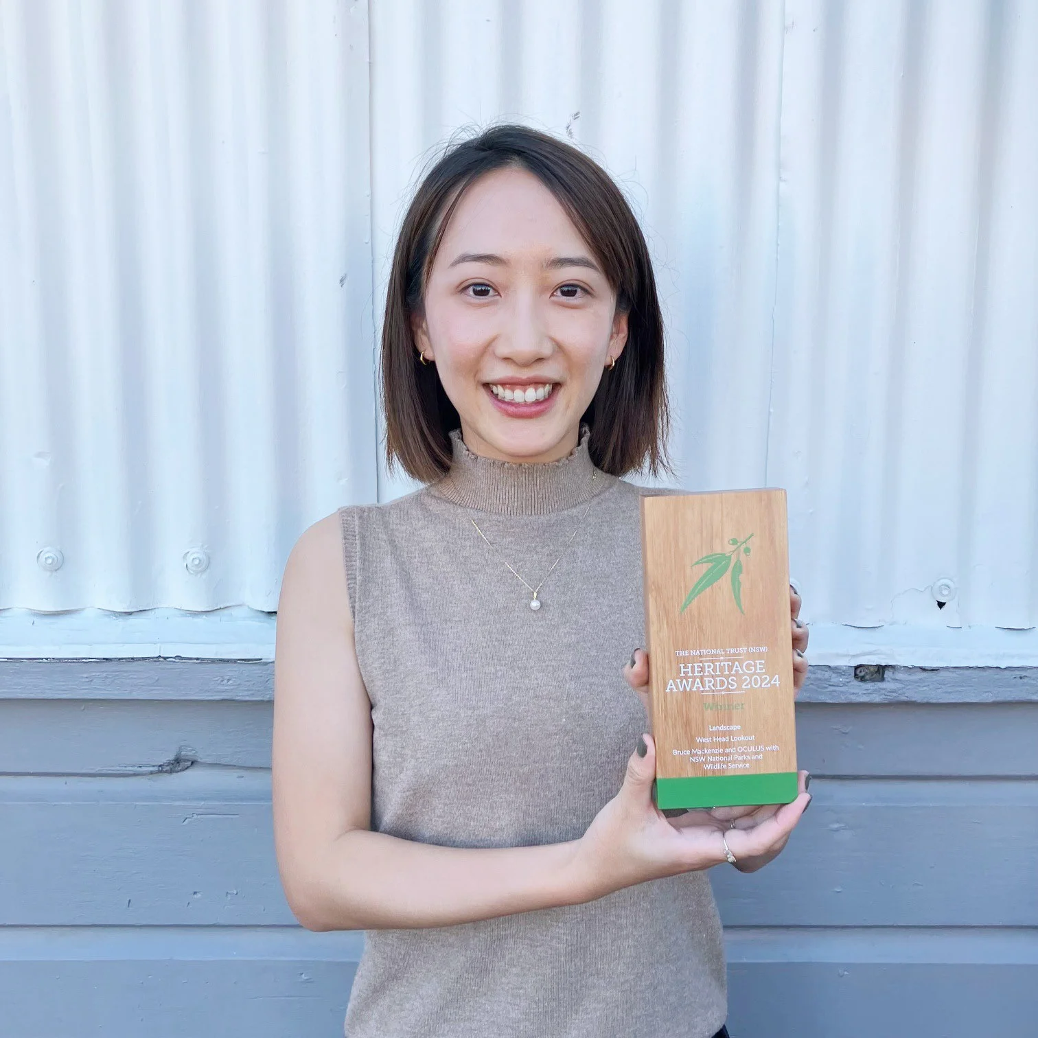 A photograph of a smiling person proudly holding a timber trophy.