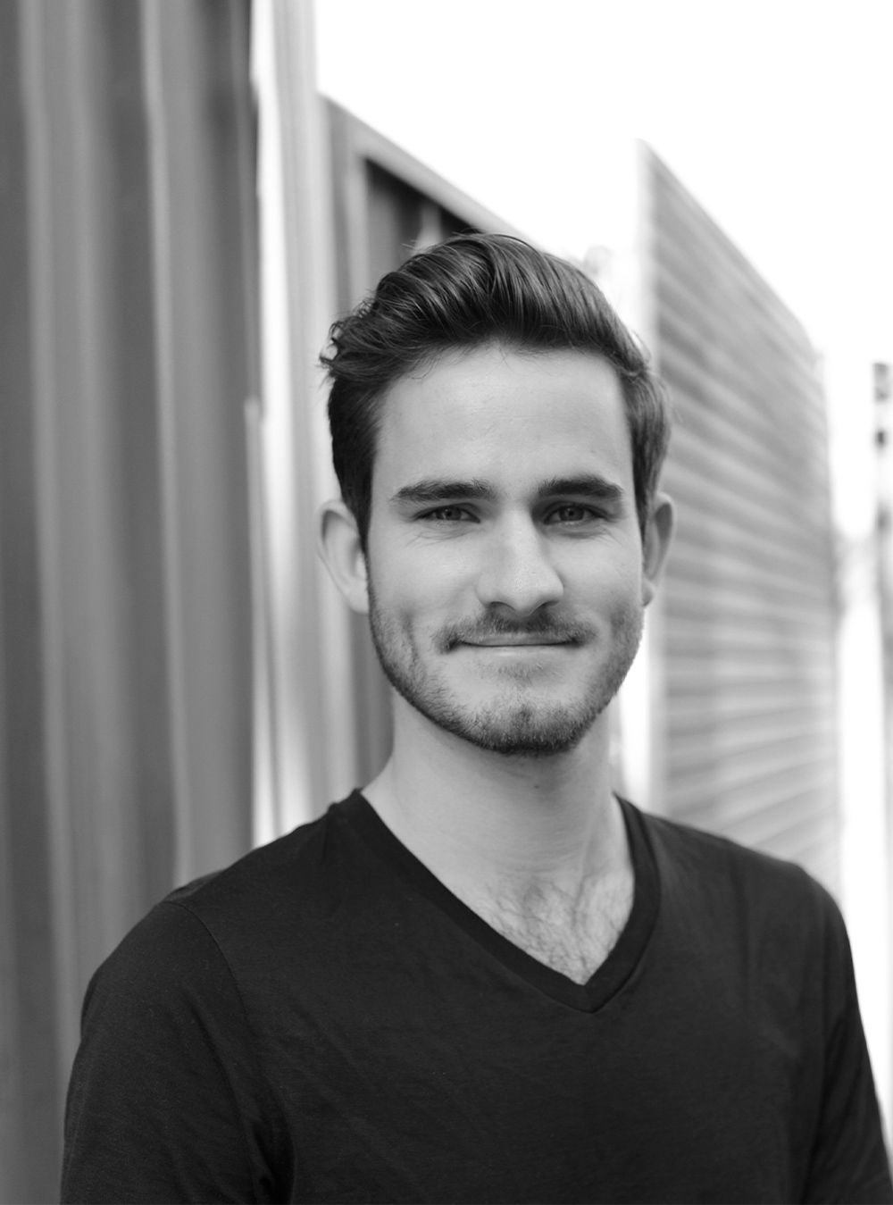 A black and white headshot of a person in an inner city laneway.