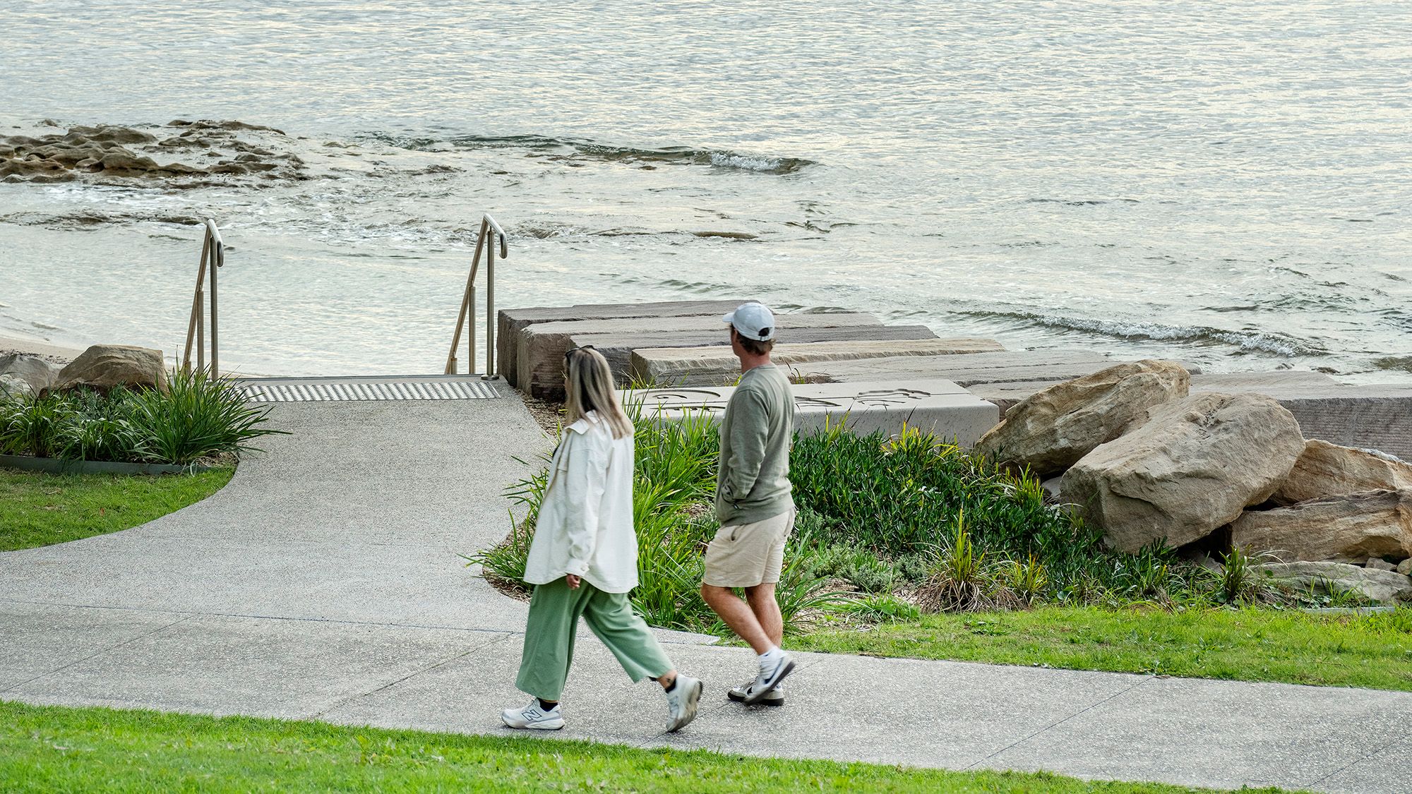 Couple walk alongside the bay and gaze at the water.