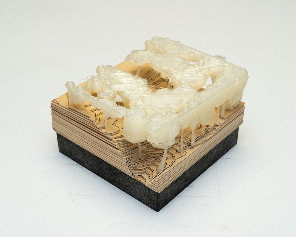 A photo of a small conceptual landscape model on a plywood base.