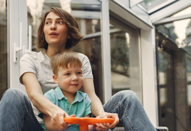 Mother and son ride on a slide car through the living room