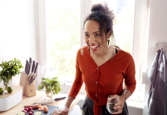 Young woman standing in kitchen and laughing