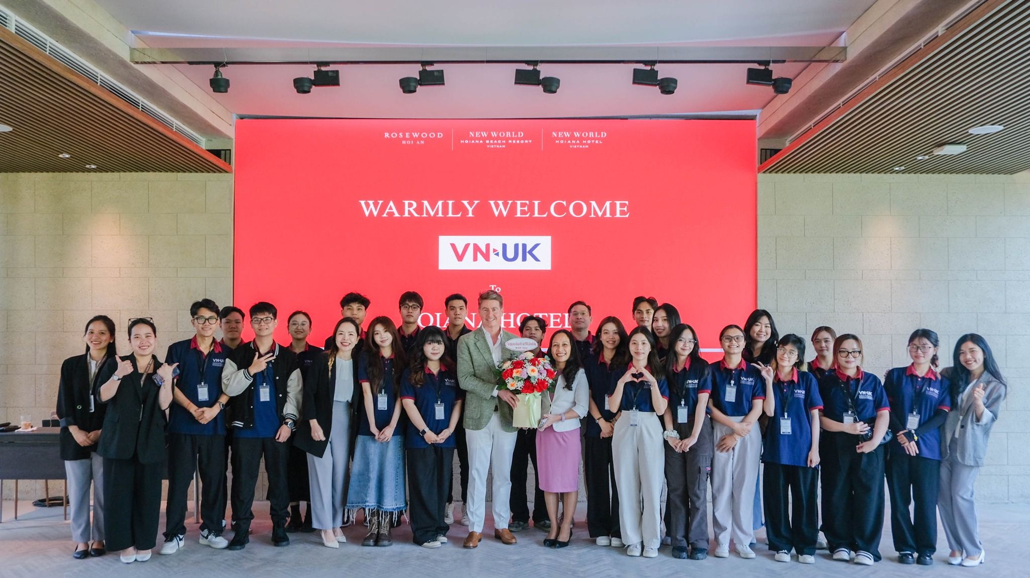 a group of people are posing for a picture in front of a large screen .