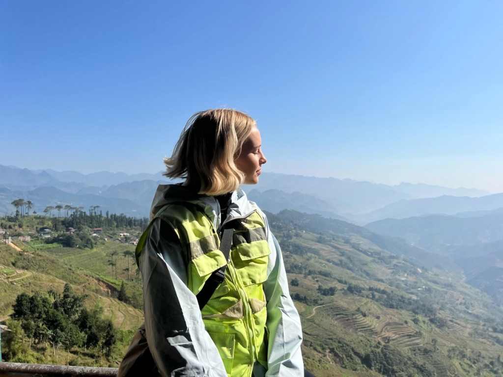 a woman is standing on a balcony overlooking a mountain range .