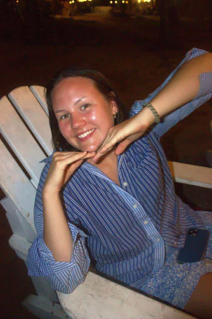 a woman in a blue striped shirt is sitting in a white chair