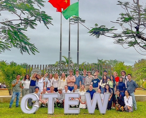 a group of people are posing for a picture in front of a sign that says ctew .
