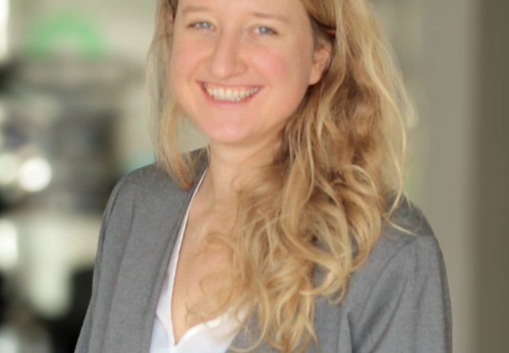 a woman with long blonde hair and a gray jacket is smiling for the camera .
