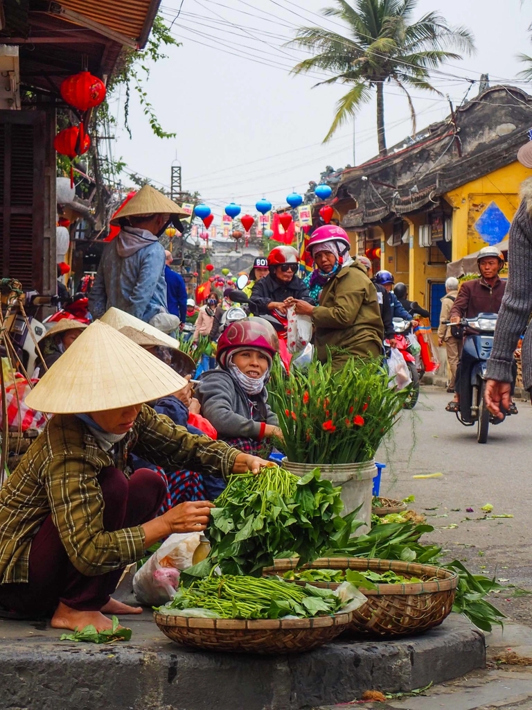 a group of people are selling vegetables on the side of the road