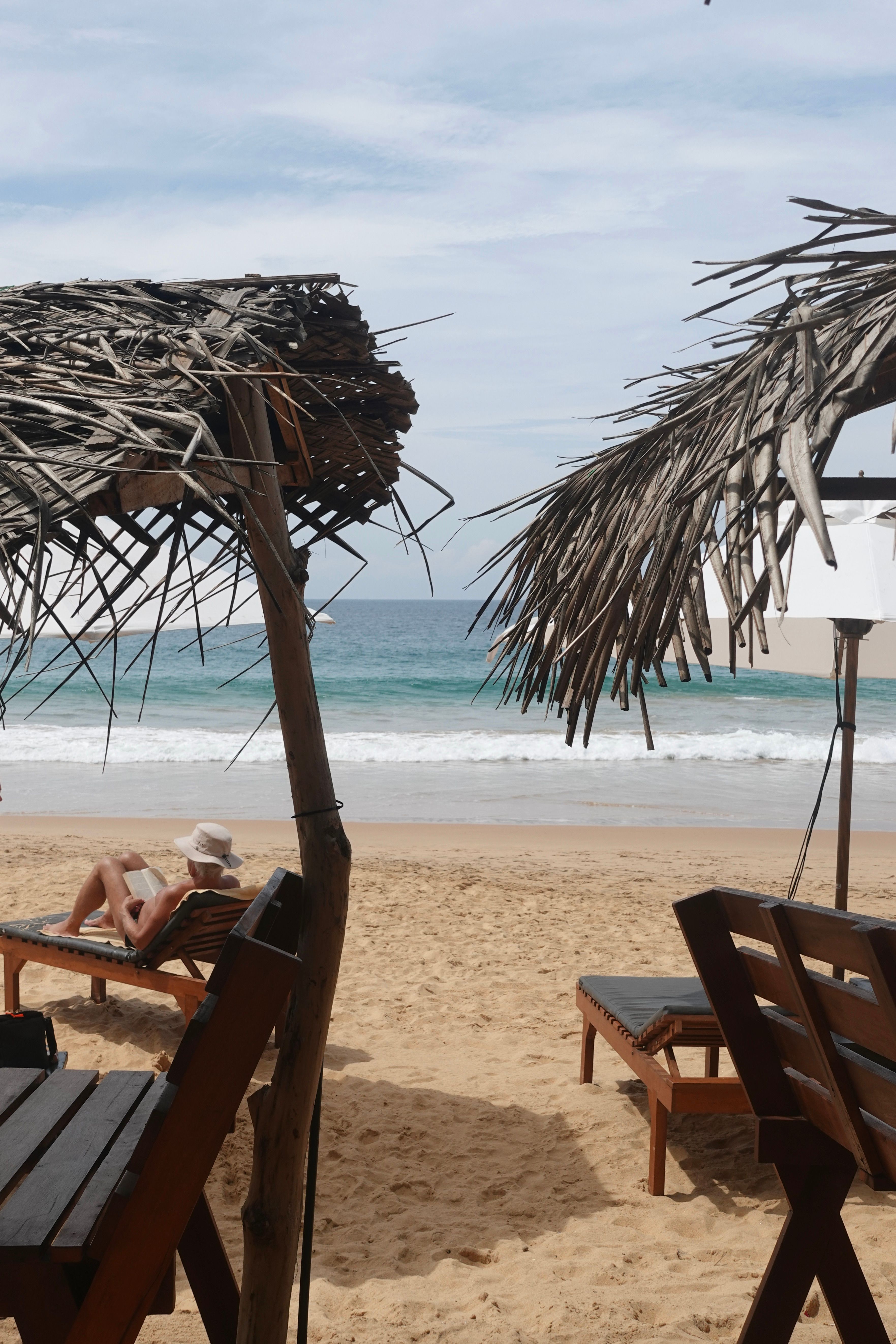 a woman sits under an umbrella on the beach