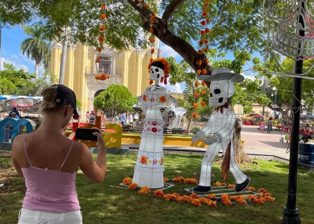 a woman is taking a picture of a skeleton couple in a park .