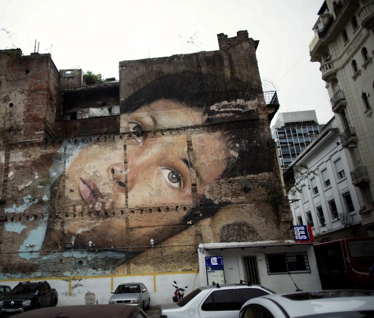 a large mural of a woman 's face on the side of a building .