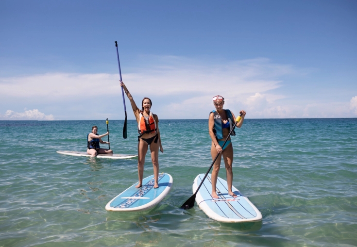 to kvinner står på paddle boards i havet.