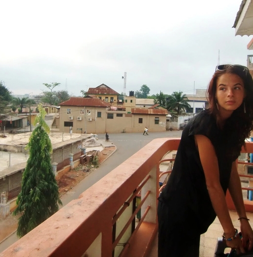 a woman is standing on a balcony holding a suitcase .