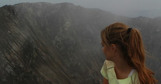 a woman is sitting on top of a mountain looking at the view .