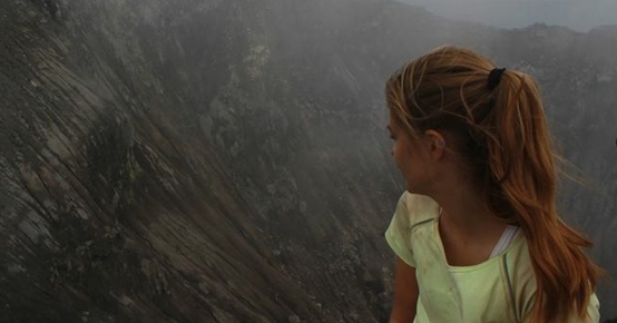 a woman is sitting on top of a mountain looking at the view .
