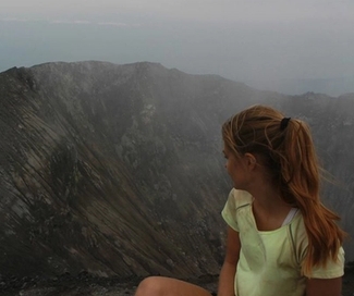a woman is sitting on top of a mountain looking at the view .