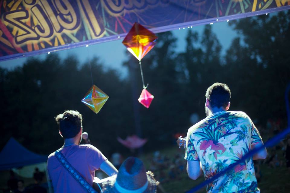 two men are playing guitars and singing into microphones at a music festival .