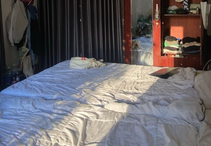 a bedroom with a bed and a wardrobe filled with clothes .