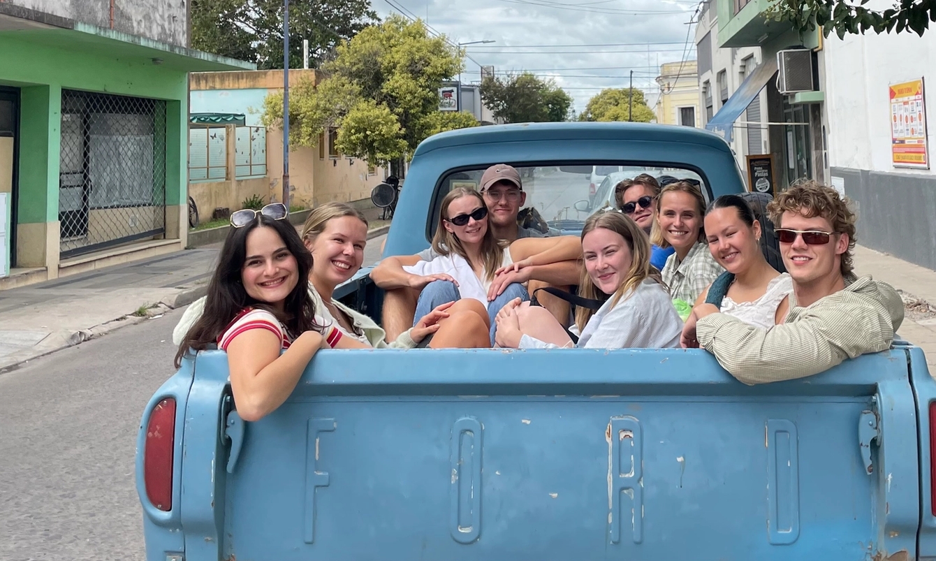 a group of people are sitting in the back of a blue truck .