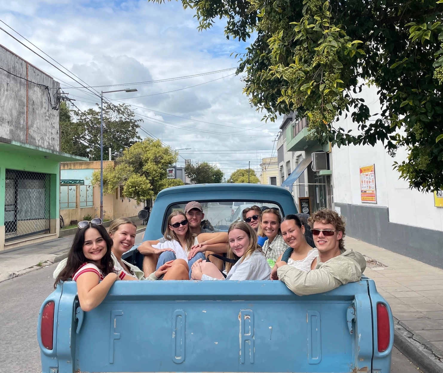 a group of people are sitting in the back of a blue truck .