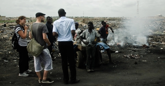 a group of people are standing in front of a pile of trash