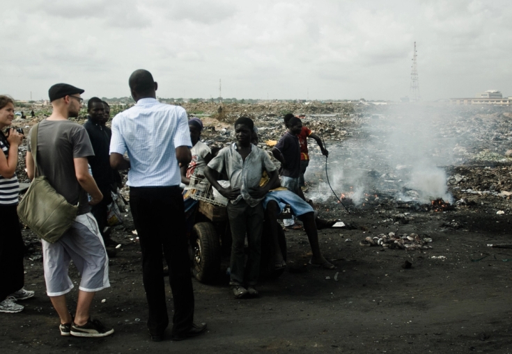 en gruppe mennesker står foran en bunke affald
