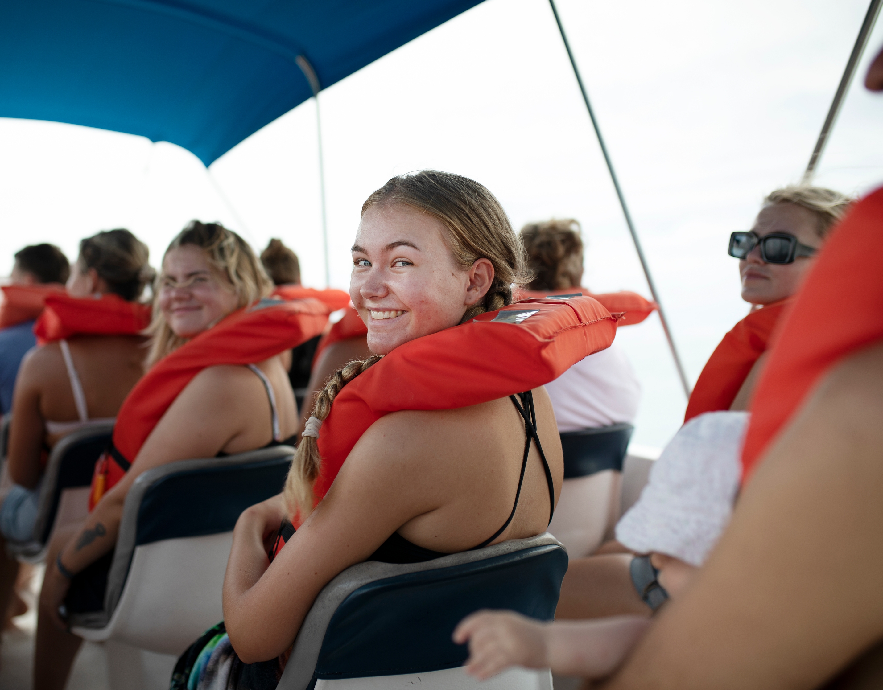 a group of people are sitting on a boat wearing life jackets .