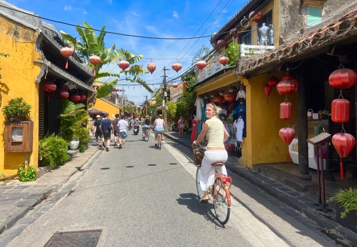 en kvinne sykler ned en smal gate.