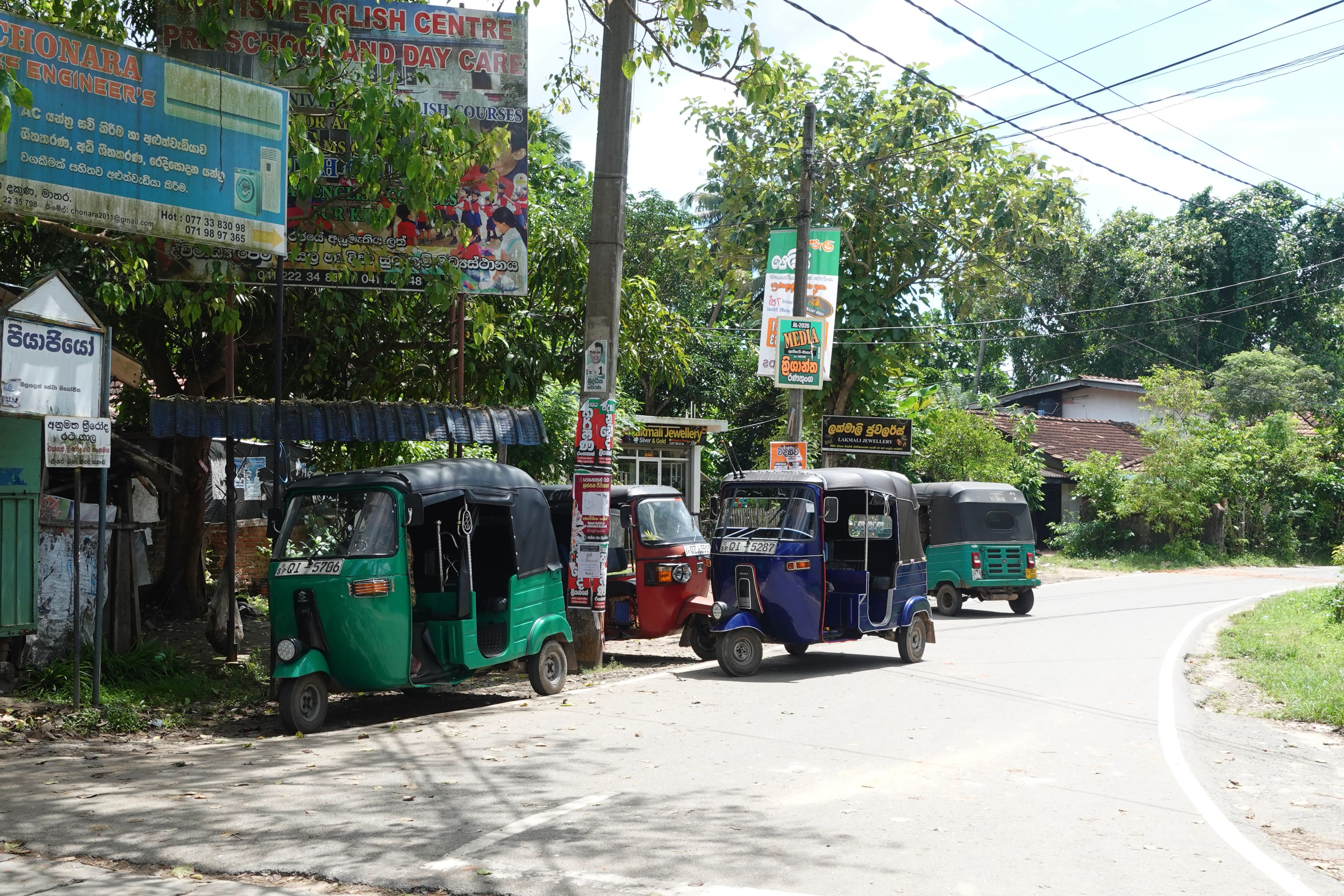 a row of three wheeled vehicles are parked on the side of a road .