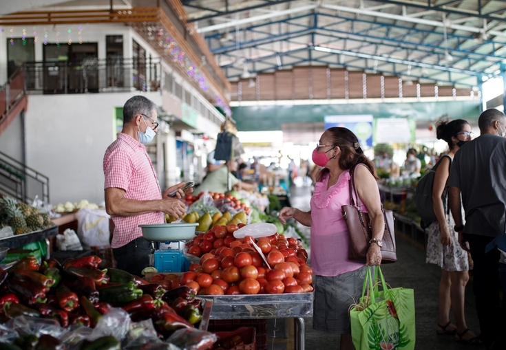a group of people are shopping at a market wearing face masks.
