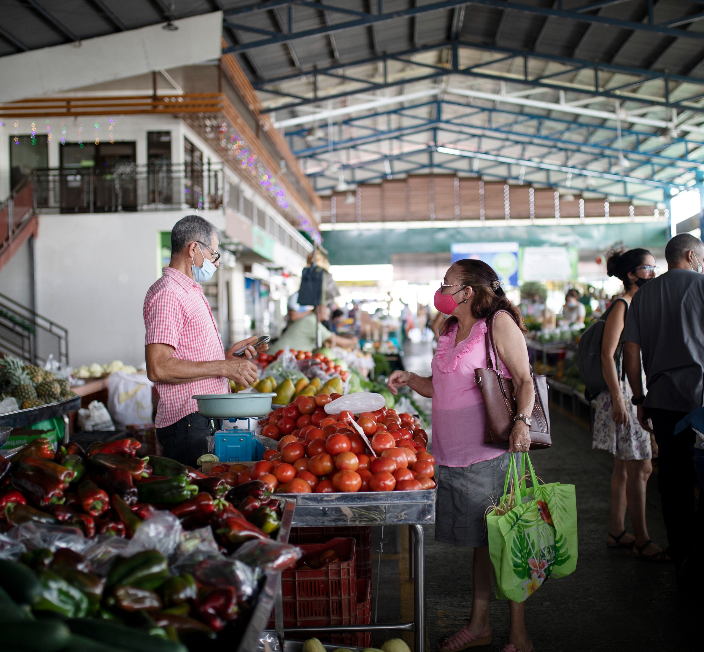 a group of people are shopping at a market wearing face masks.