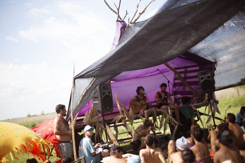 a group of people are sitting under a purple tent .