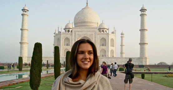 en kvinne står foran taj mahal i india.