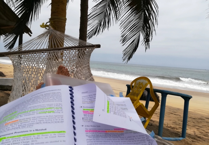 en person läser en bok i en hängmatta på stranden.