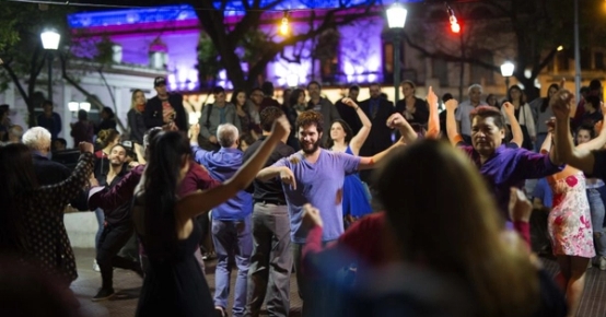 a group of people are dancing in a park at night