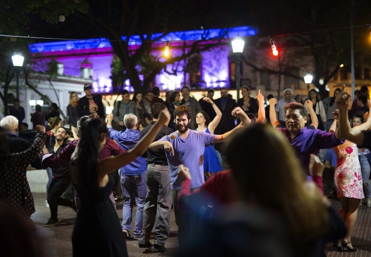 en gruppe mennesker danser i en park om natten