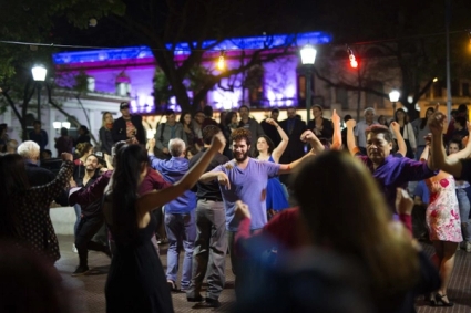 a group of people are dancing in a park at night