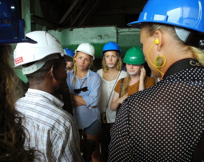 a group of people wearing hard hats are standing around talking to each other .
