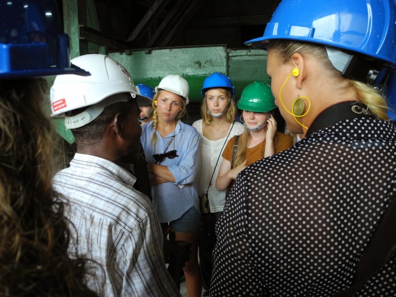 a group of people wearing hard hats are standing around talking to each other .