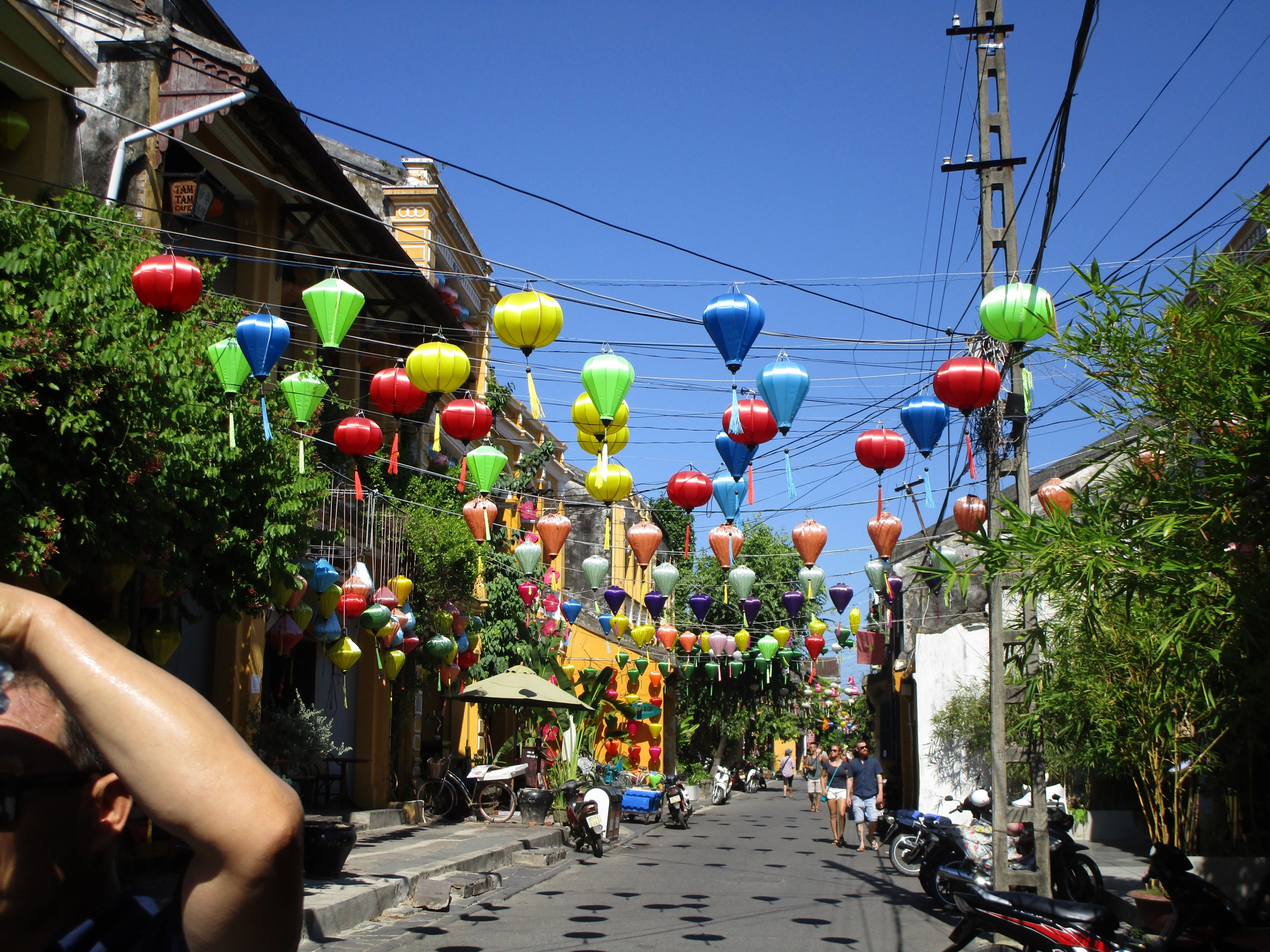 a person is taking a picture of a street decorated with colorful lanterns .