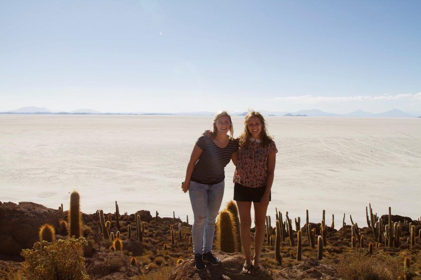 two women are standing next to each other in the desert .